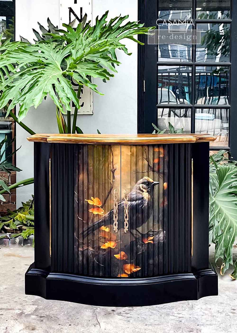Avian Dreamscape decoupage tissue paper applied to a black curved cabinet, featuring a dark bird with golden leaves on the front doors.