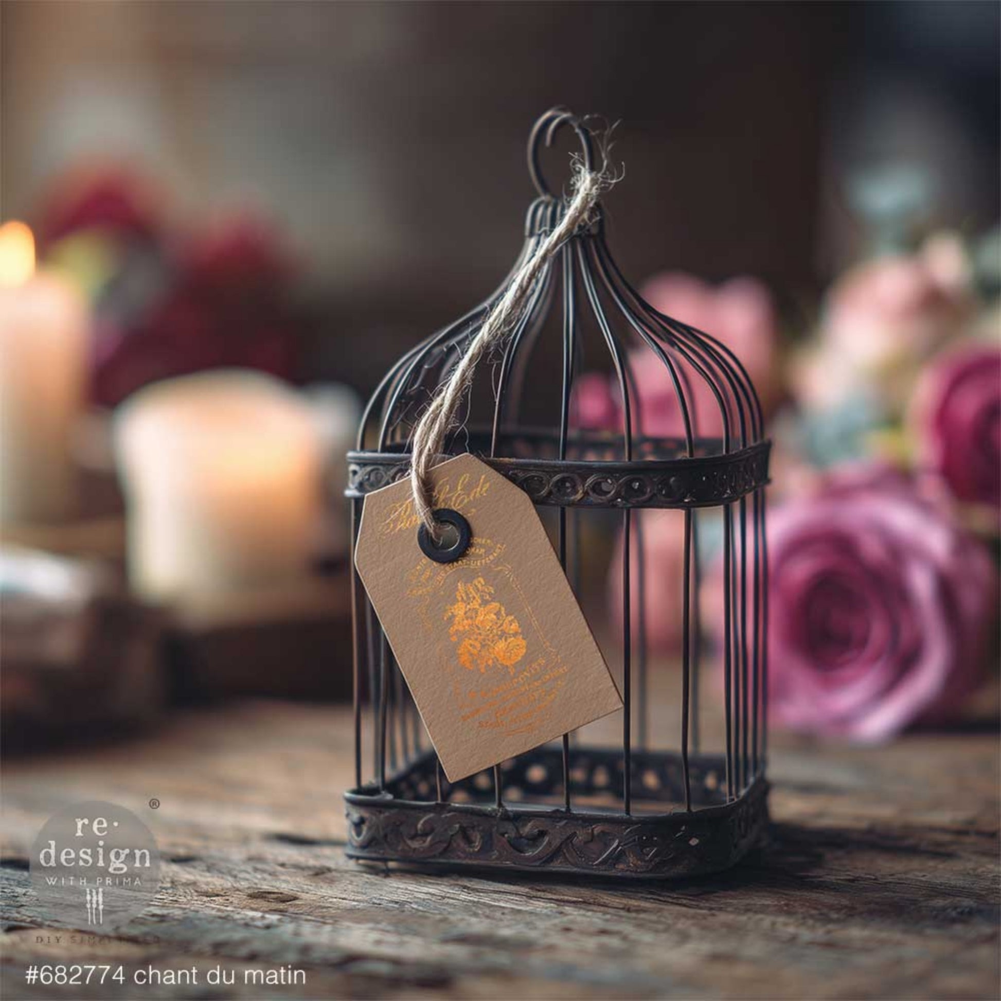 Chant Du Matin gold transfer applied to a kraft tag hanging from a decorative birdcage with soft floral vintage styling.