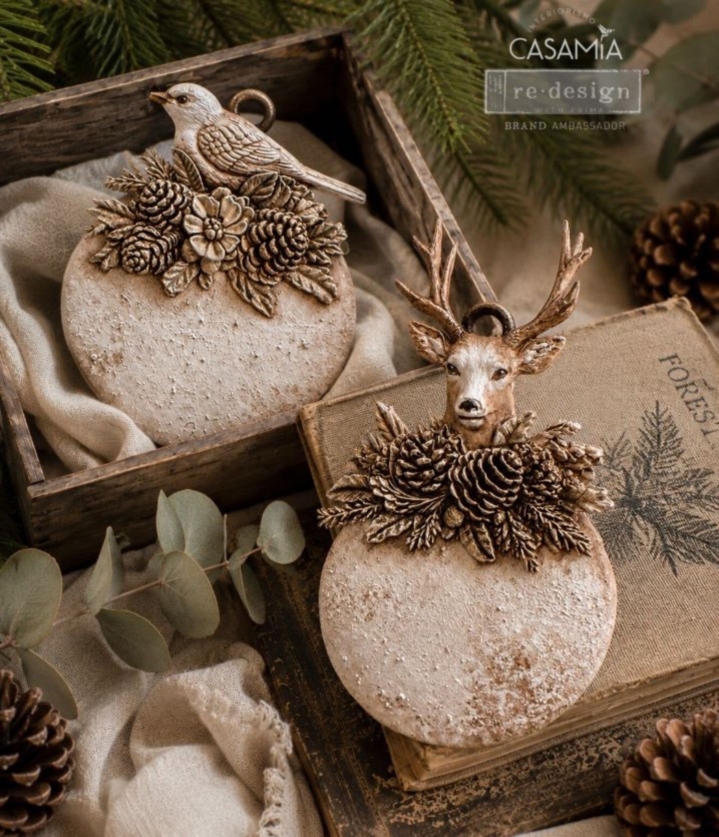 Two rustic ornament plaques featuring a woodland bird and antlered deer with pinecones and evergreen castings.