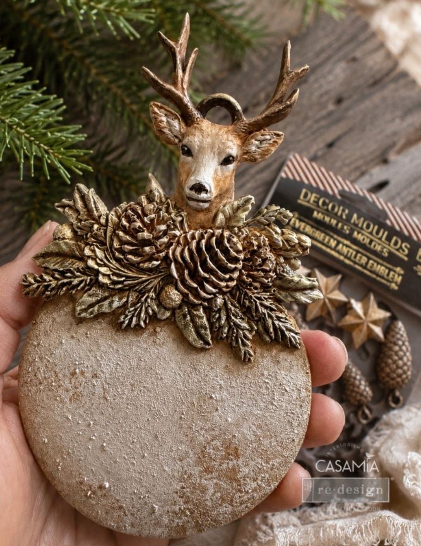 Close-up of an Evergreen Antler Emblem deer ornament with pinecones, leaves, and evergreen details.