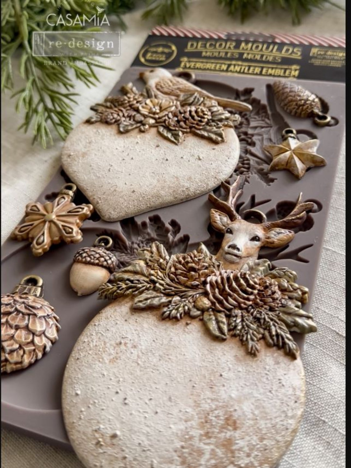 Evergreen Antler Emblem Décor Mould shown with finished bird, deer, pinecone, acorn, star, and ornament castings.