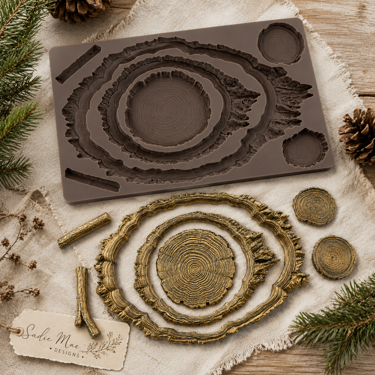 Evergreen & Embers Décor Mould and gold-finished tree-ring castings styled with linen, pinecones, evergreen branches, and Sadie Mae Designs branding.