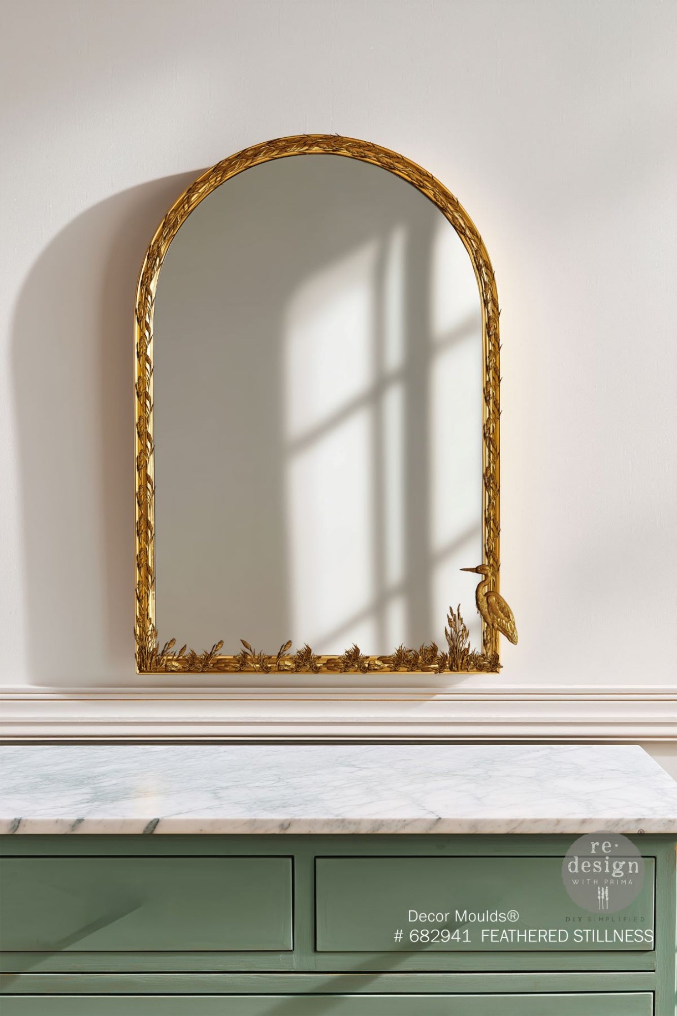 Gold castings made from the Feathered Stillness silicone mould featuring a long-legged bird, water grasses, cattails, and botanical accents on a mirror