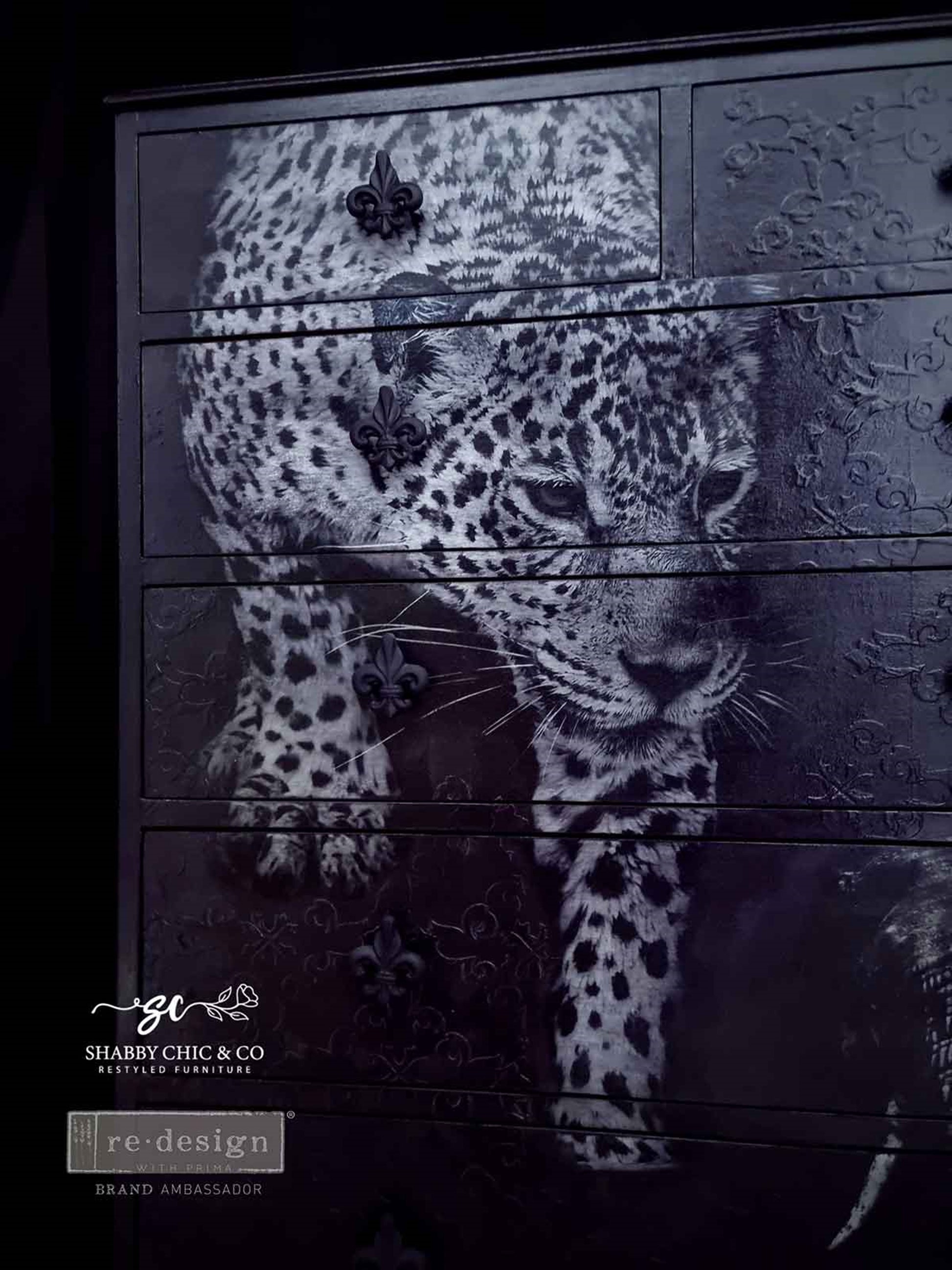 Close-up of Feline Gaze leopard decoupage design applied across black dresser drawers with fleur-de-lis hardware.
