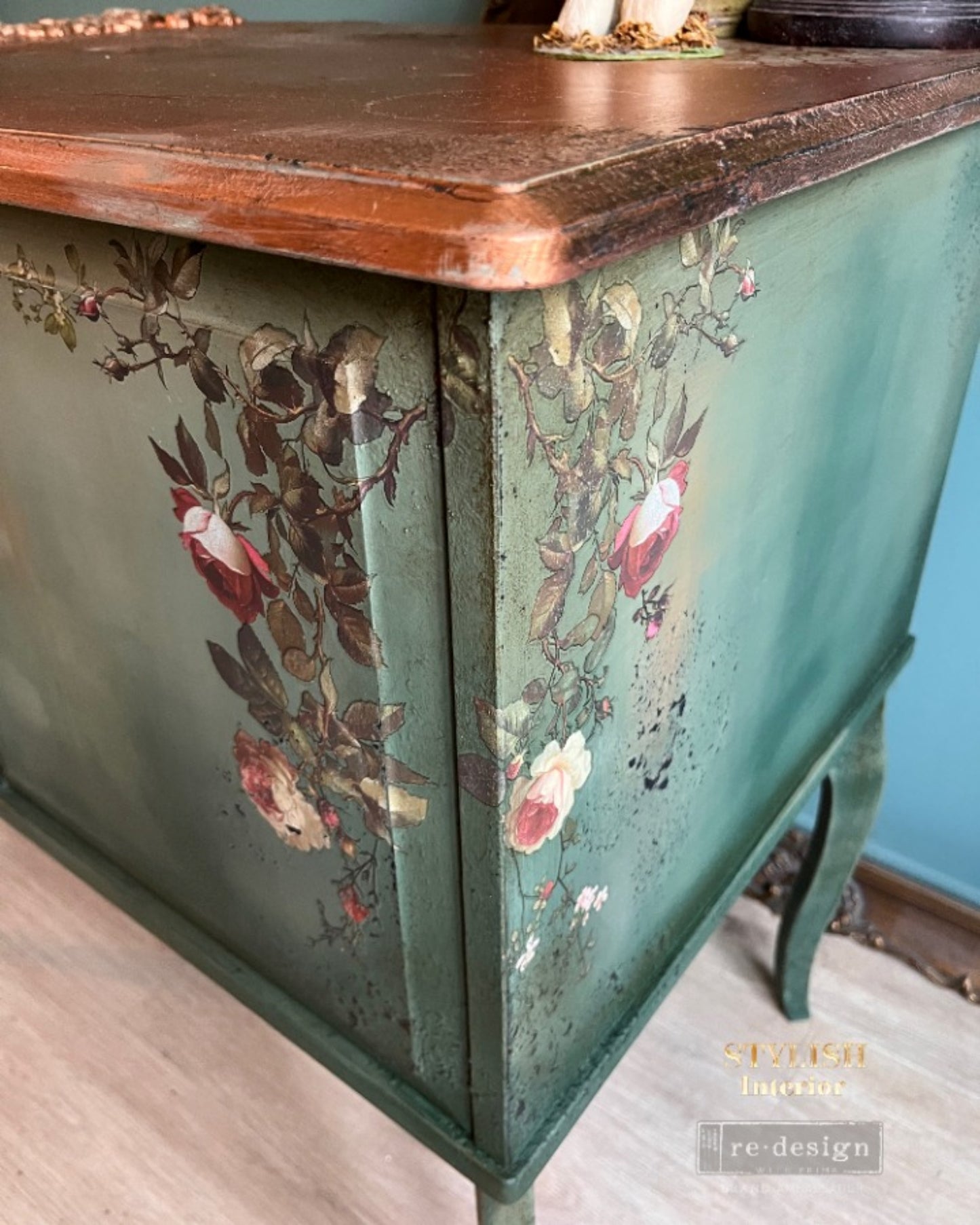 Midnight Rose floral transfer sheet set with detailed roses, buds, greenery, and small blossom accents on blue cabinet.