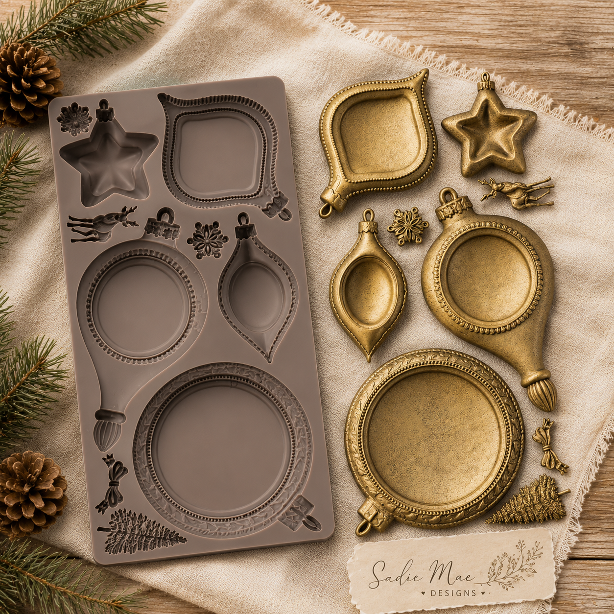 Noel Elegance Decor Mould with finished gold castings displayed on neutral fabric with pinecones and greenery.