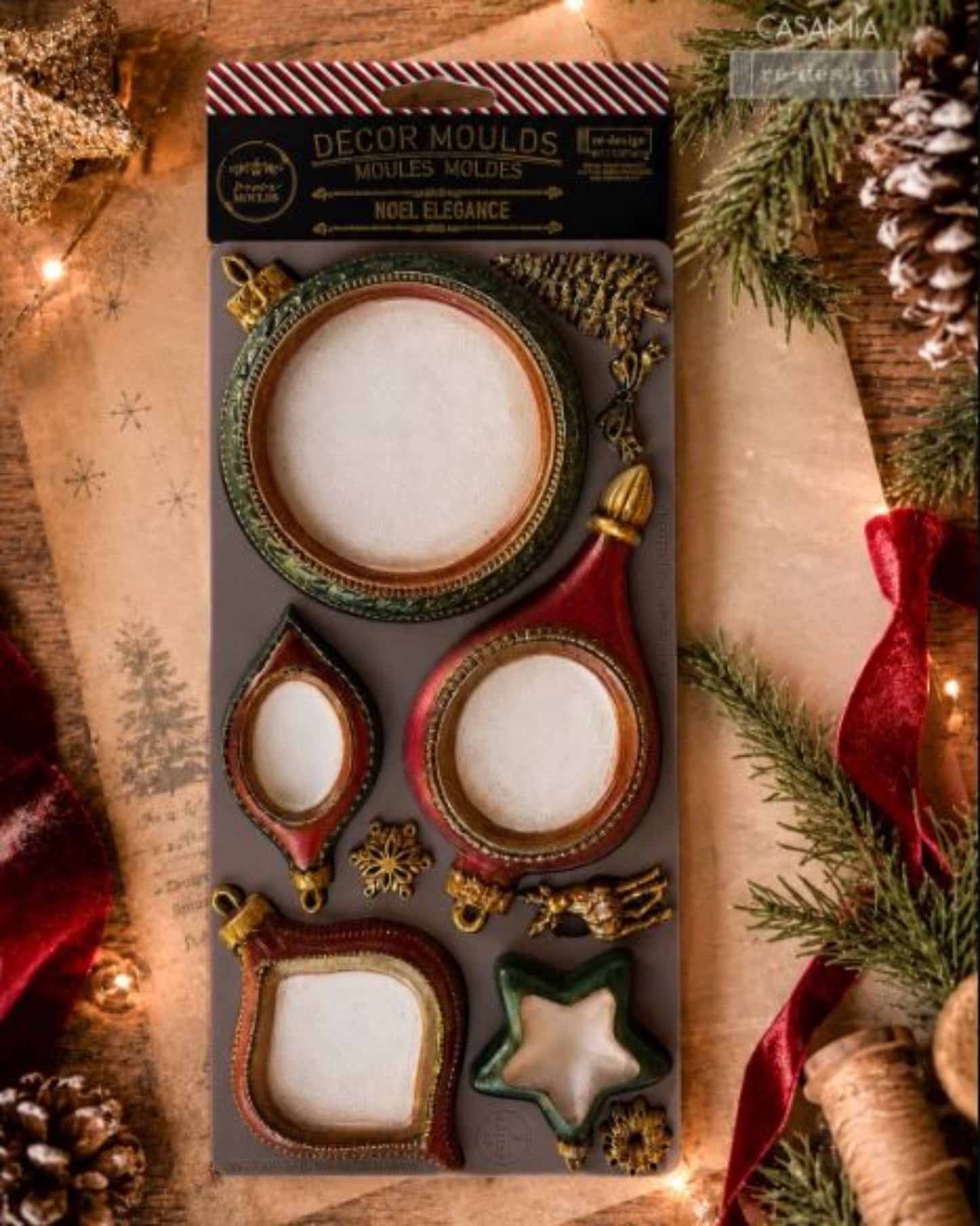 Hand holding a large round finished ornament made from the Noel Elegance mould, with other ornament samples in the background.