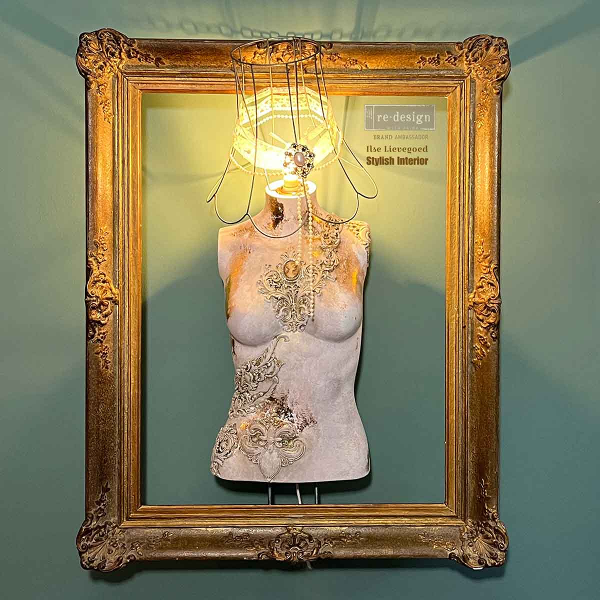 Decorative mannequin bust featuring Salon De La Belle Epoque mould embellishments, antique gold highlights, pearl strands, and an ornate frame backdrop.