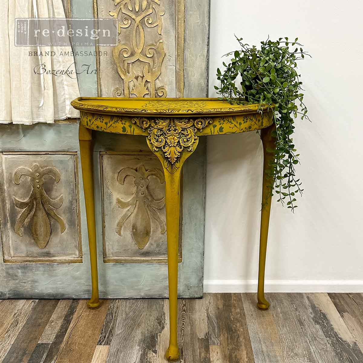 Salon De La Belle Epoque Decor Mould casting applied to the front of a mustard yellow accent table with ornate raised scrollwork, stenciled details, and vintage French styling.