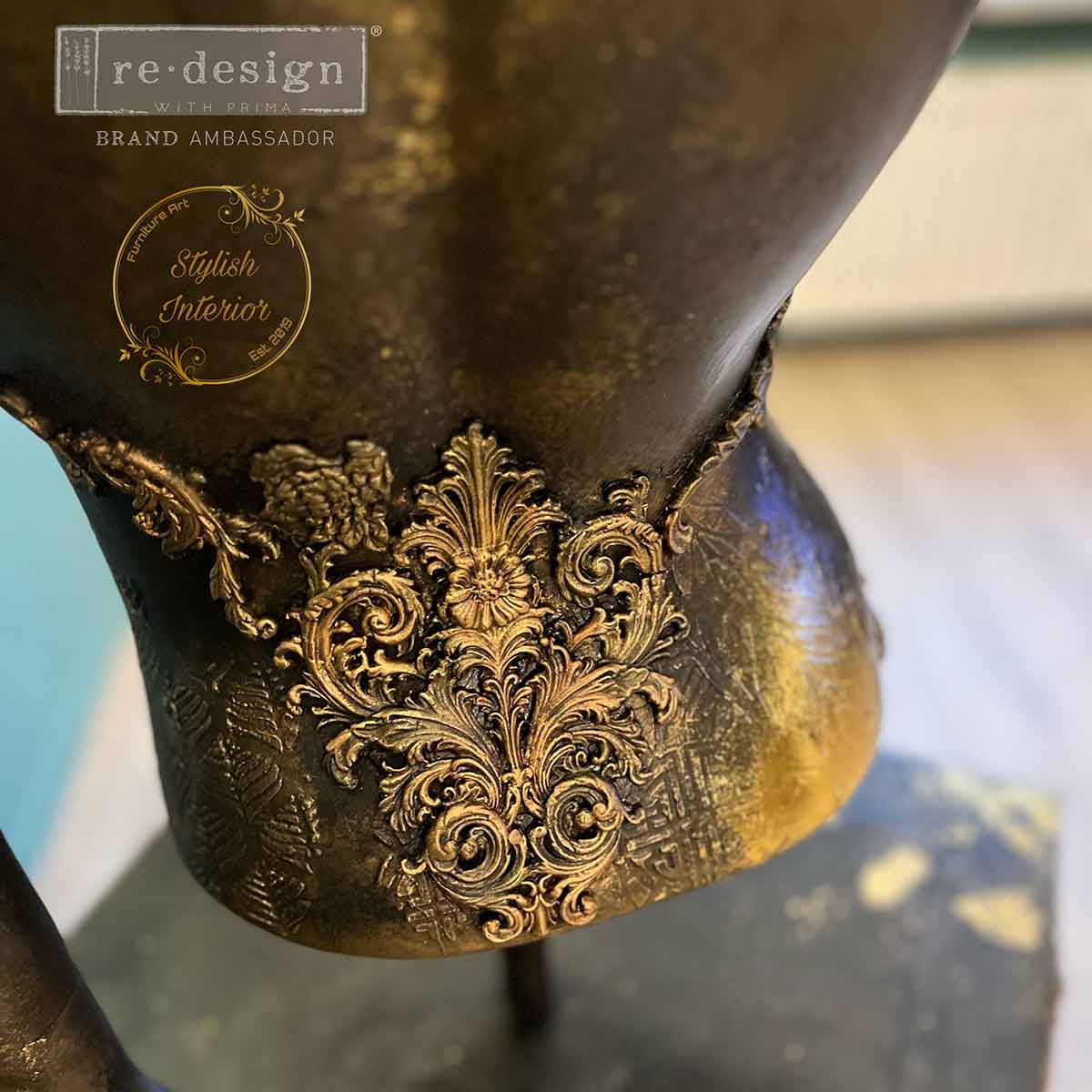 Close-up of Salon De La Belle Epoque mould embellishments on a mannequin bust, finished with antique gold highlights and textured black patina.