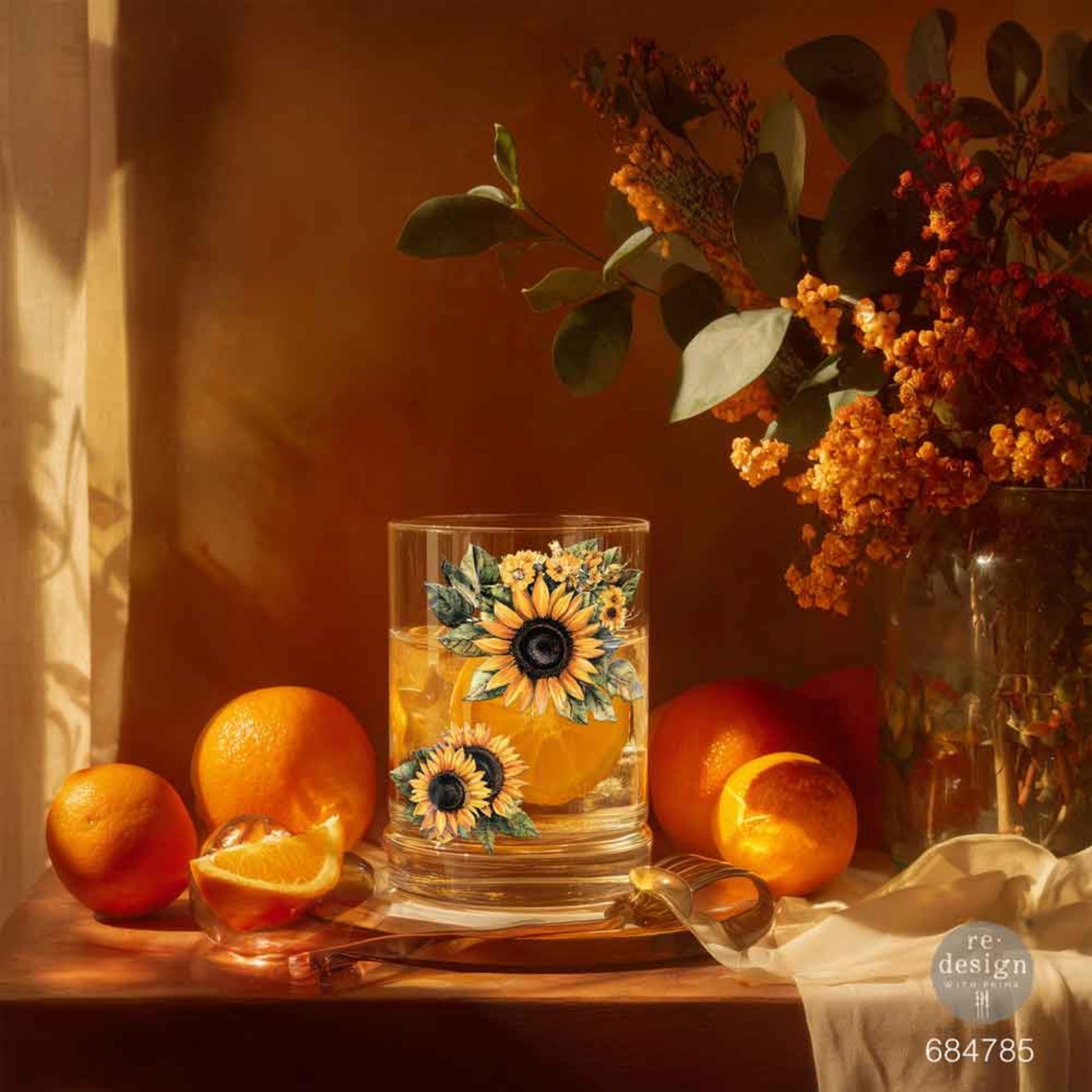 Clear drinking glass decorated with sunflower Luxe Transfers, styled with fresh oranges and autumn florals.